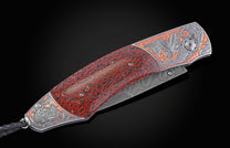 A custom folding knife with a red dinosaur bone handle, intricate silver and bronze dragon engravings, a Damascus steel blade, and a black leather lanyard.