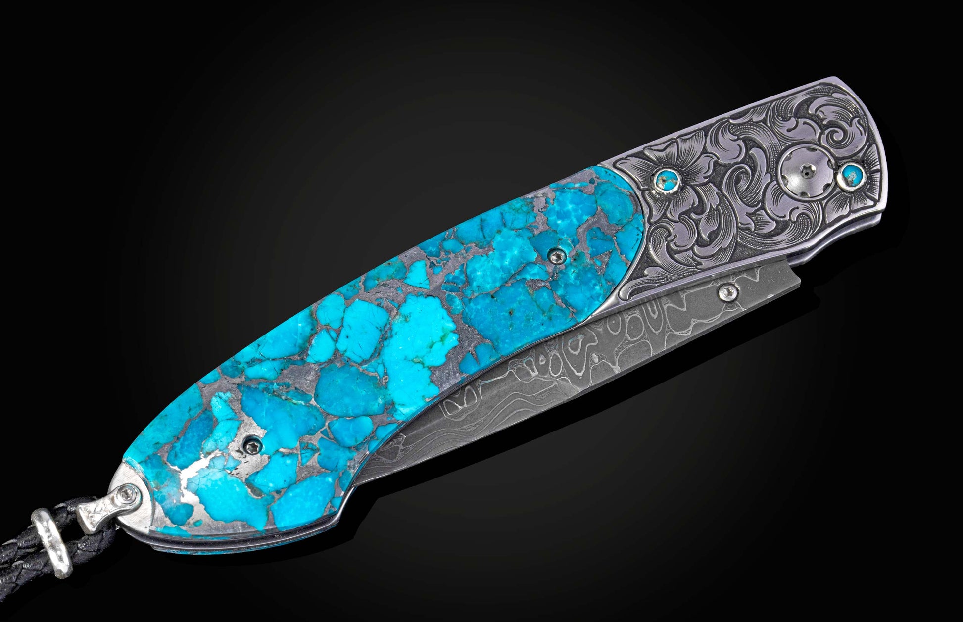 Luxury folding knife with vibrant turquoise inlay, detailed silver floral engraving, Damascus blade, and a braided black lanyard.