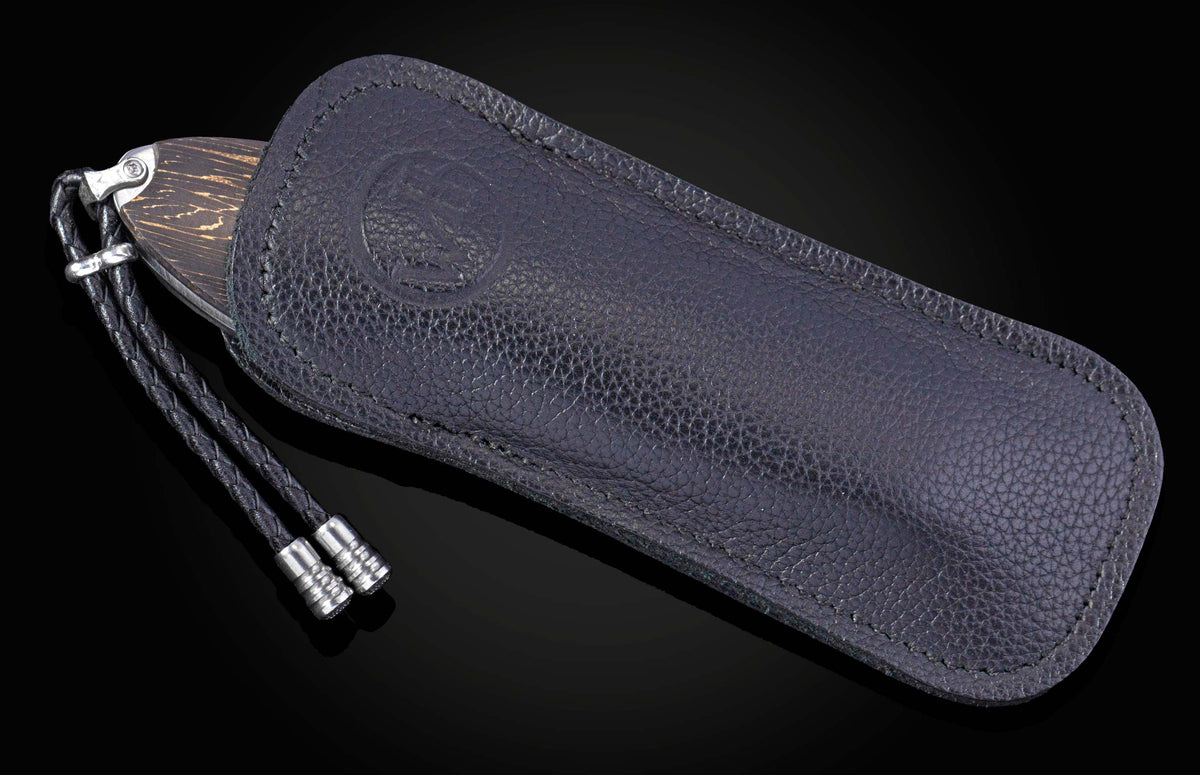 Folding knife with dark wooden handle partially visible in a dark textured leather sheath featuring an embossed logo and braided cord.