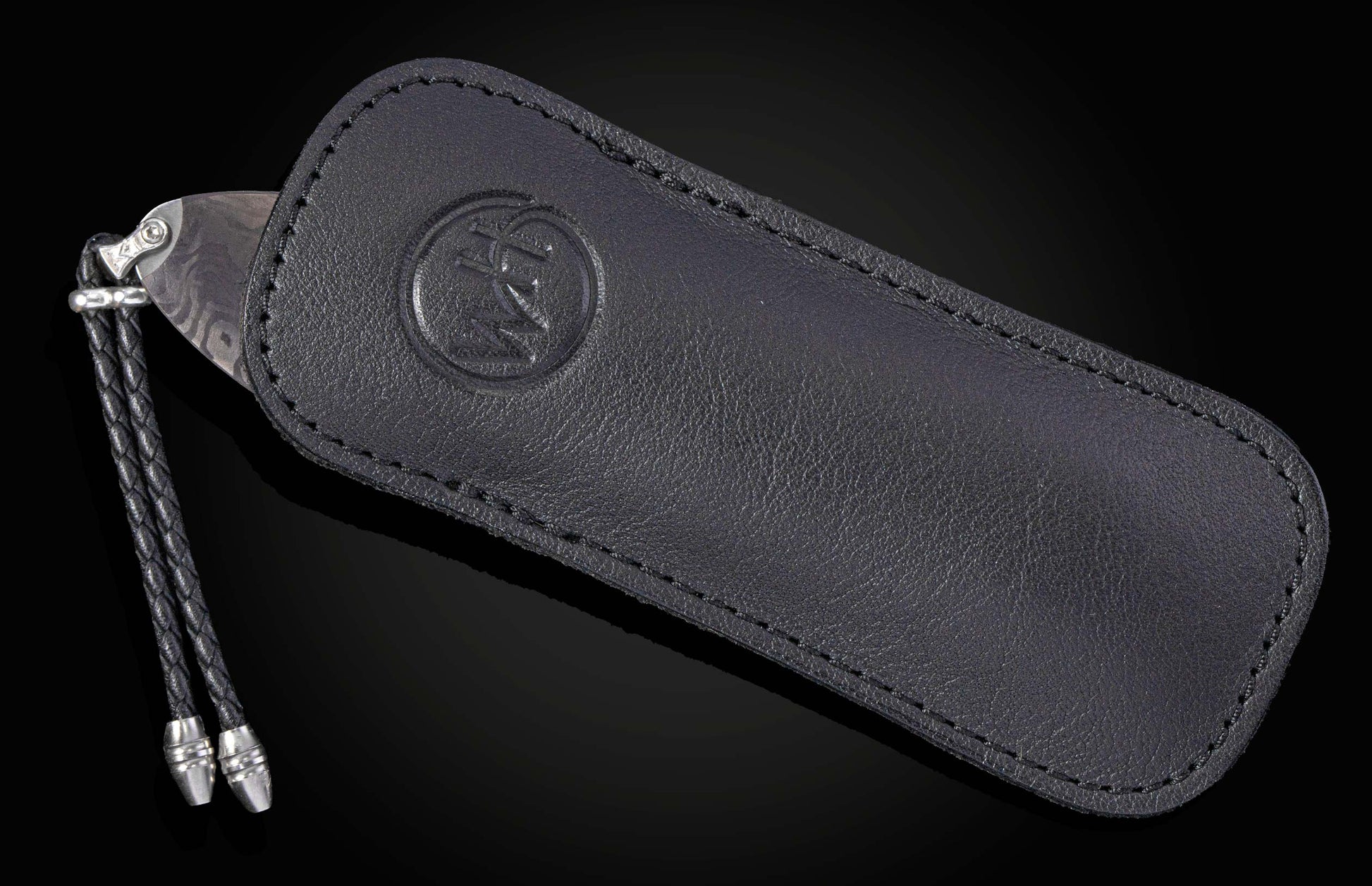 Folding knife with a patterned Damascus steel blade partially in a black leather sheath featuring an embossed logo and a braided lanyard.