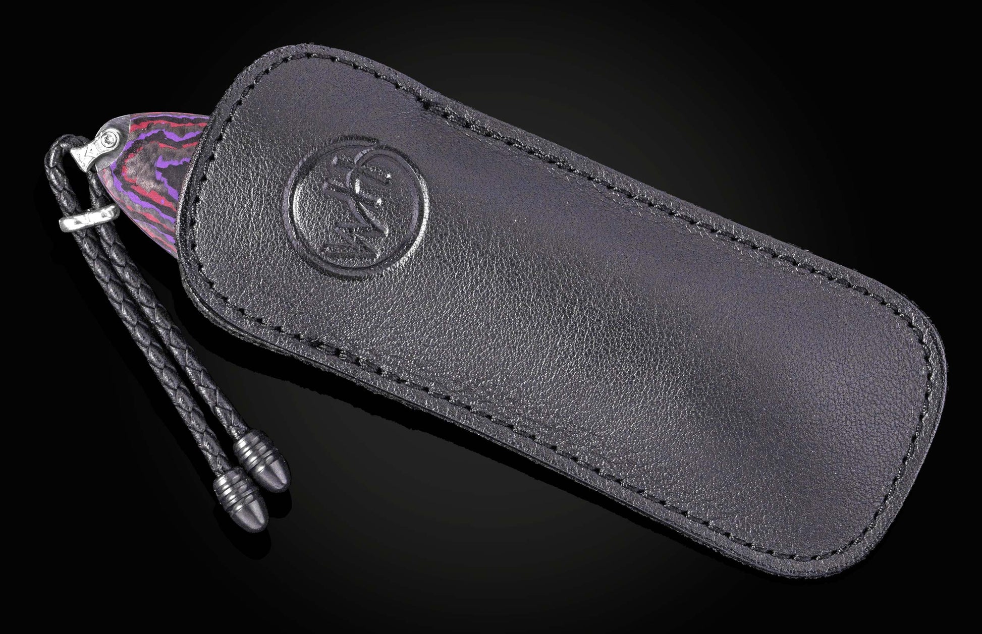 Luxury folding knife with vibrant purple and red patterned handle, by B12, in black leather sheath with embossed logo and braided cord.