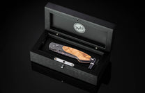 Black open box containing a William Henry knife on a black background