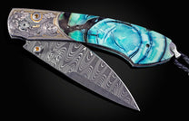 Folding knife with decorative handle and blade on a dark background
