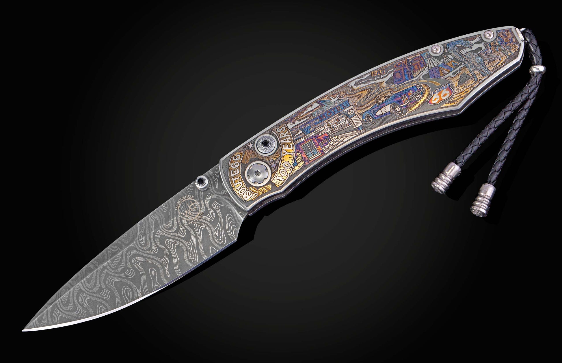Knife with a wavy Damascus steel blade and an intricately engraved, colorful handle depicting Route 66 scenes, a classic car, and "100 YEARS" text, finished with a black braided lanyard.