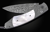 Damascus steel folding knife with wavy pattern and mother-of-pearl inlay, by William Henry, side view on black background