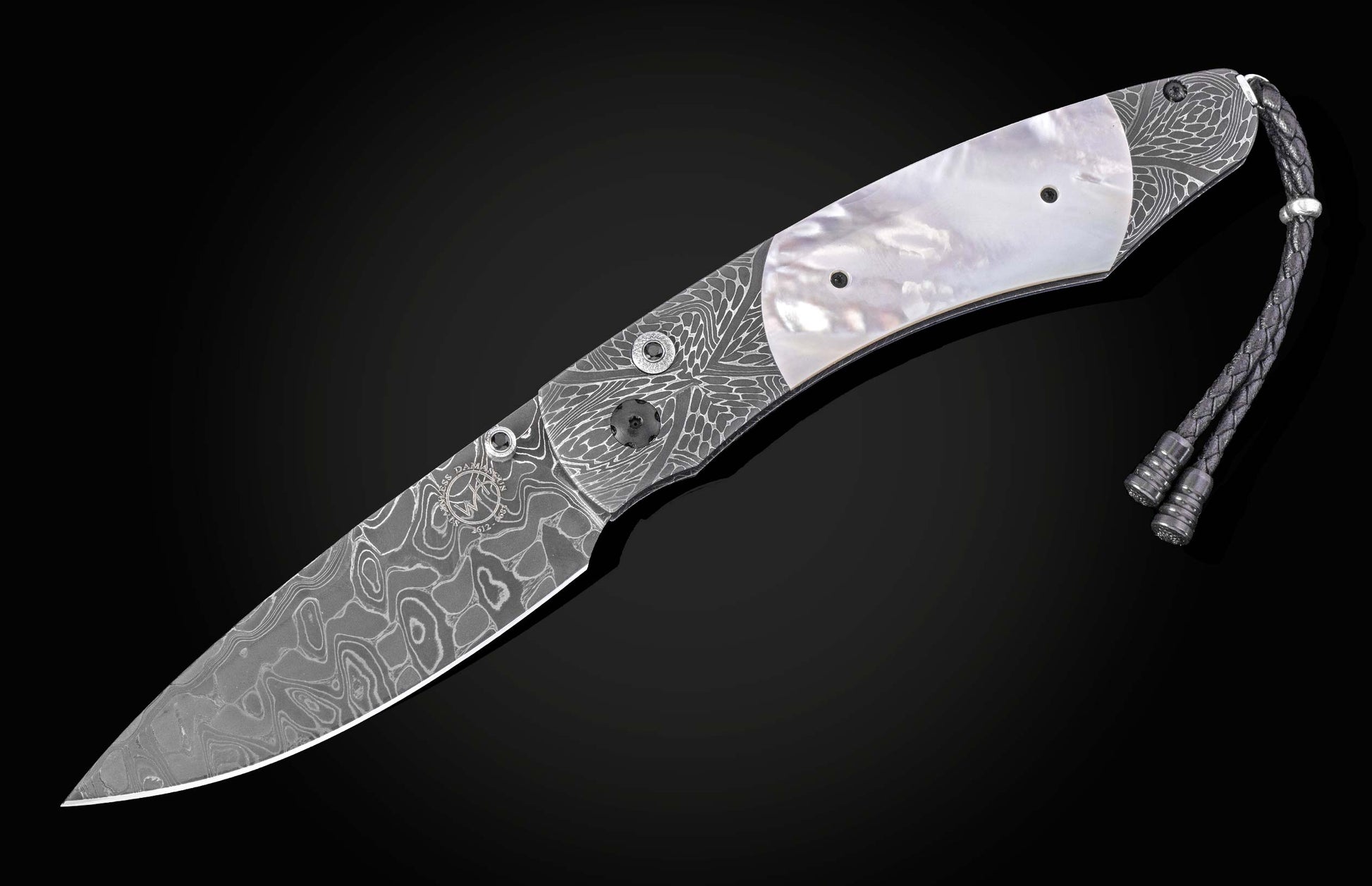 Damascus steel knife with silver wave pattern and mother-of-pearl inlay, featuring braided cord lanyard, side view on black background