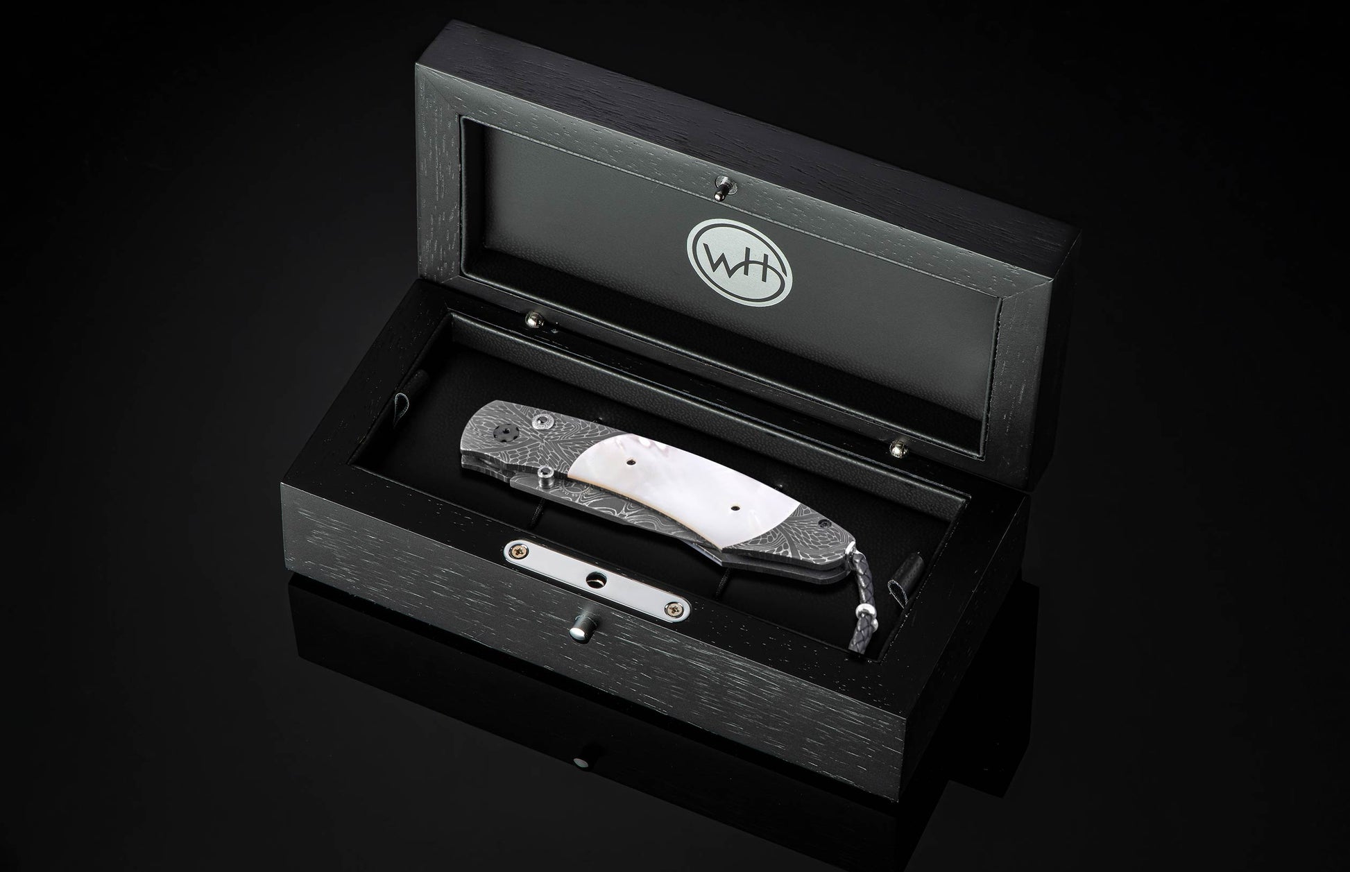 Silver folding knife with damascus steel handle and mother-of-pearl inlay by William Henry, displayed in black presentation box, top-down view