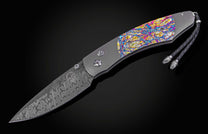 Decorative knife with colorful handle and damascus blade on a black background