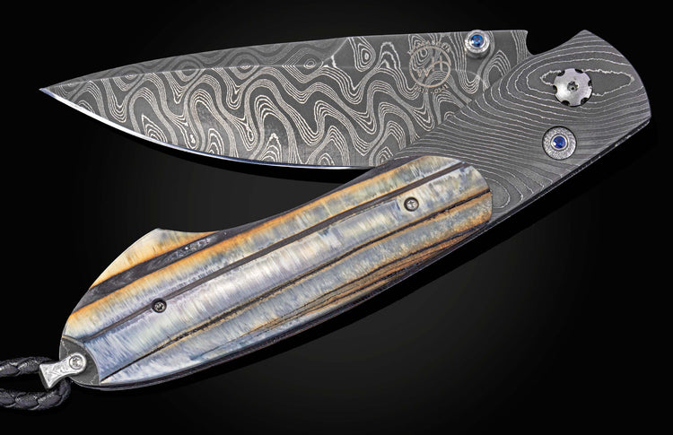 Partially open folding knife with a wavy Damascus steel blade, striped blue-gray handle, and blue gem accents.