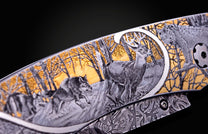 Knife with an engraved handle showcasing a forest scene of deer, wolves, and a lynx with gold accents and a Damascus pattern.