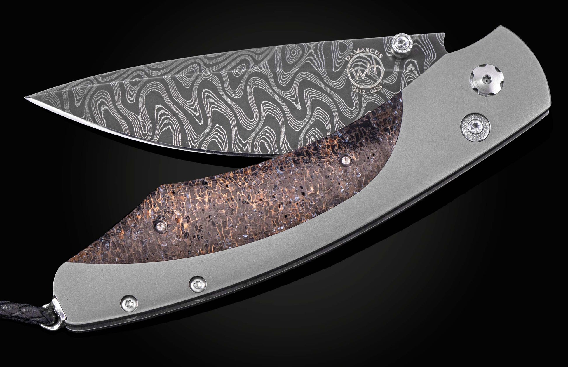 Partially open folding knife with a wavy Damascus blade, textured fossilized coral handle inlay, matte titanium frame, and braided lanyard.