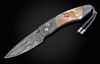 Decorative folding knife with artistic blade and embellishments on a dark background