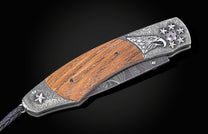 Folding knife with wooden handle and decorative blade on a black background