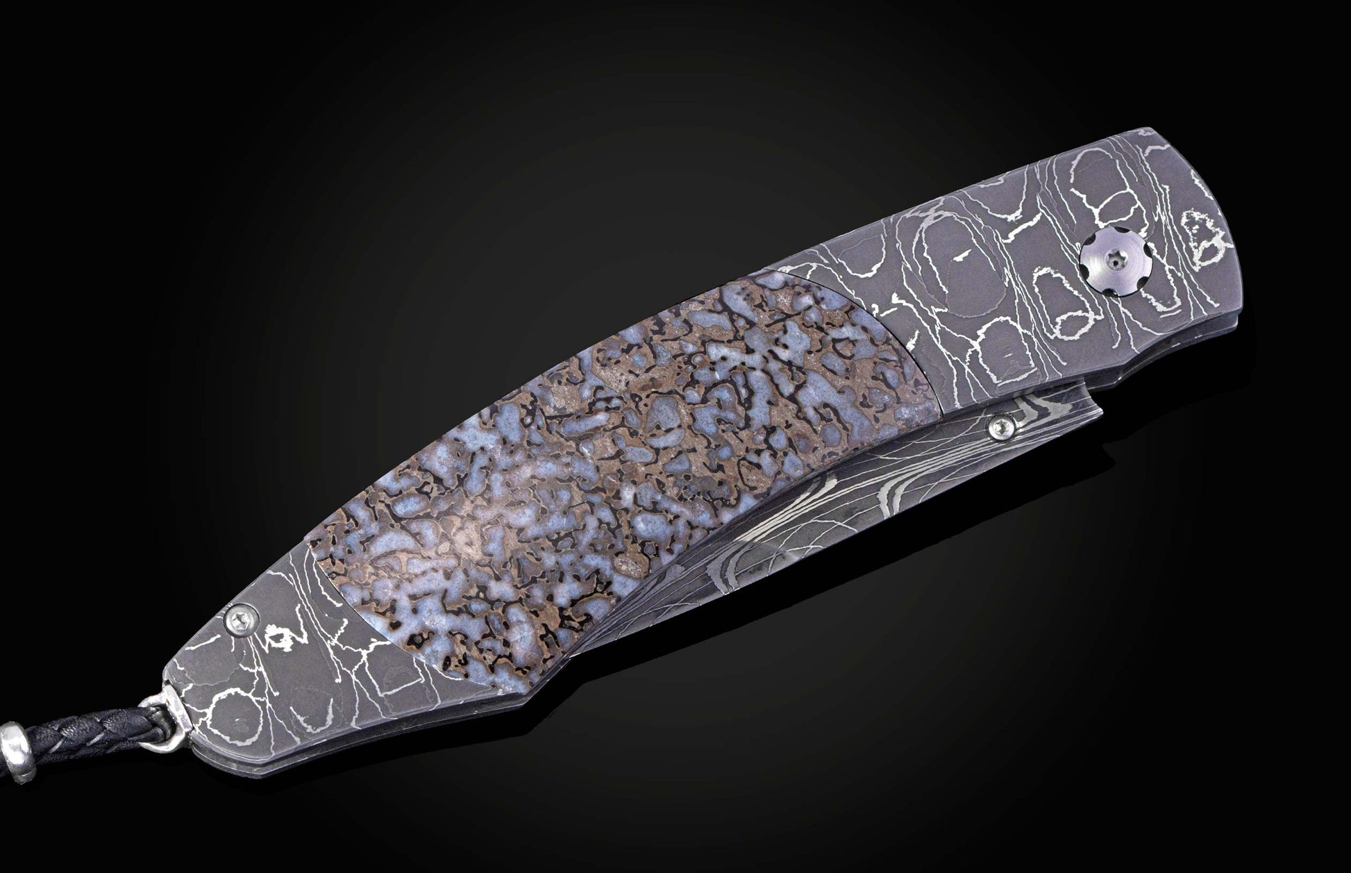 Folding knife with a dark damascus steel handle, a blue-brown fossilized inlay, and a braided lanyard.