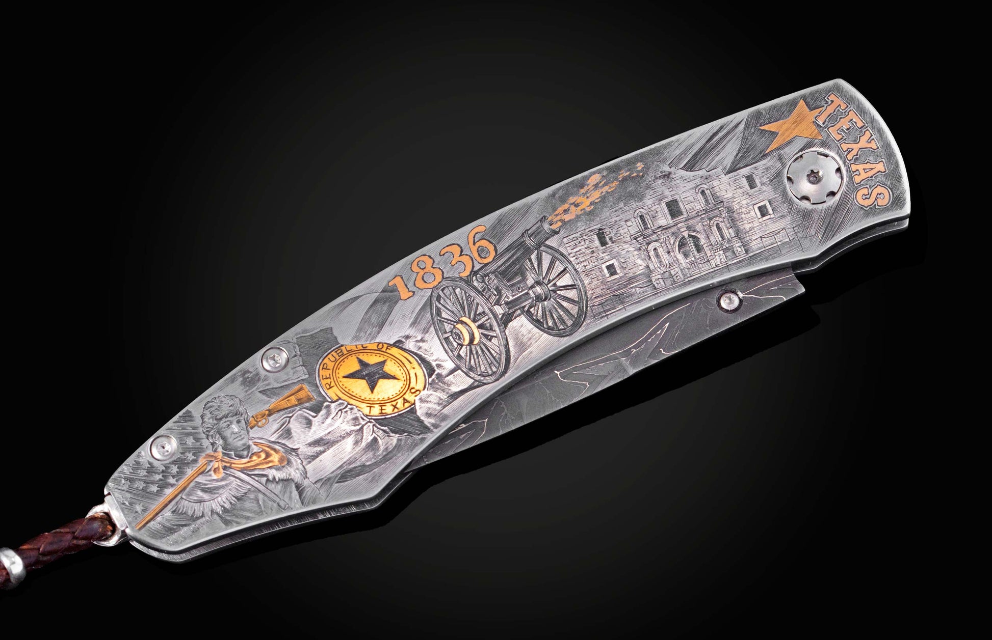 Decorative folding knife engraved with images from the Alamo on a black background