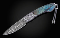 Decorative knife with damascus blade and fossilized woolly mammoth tusk scales on a black background