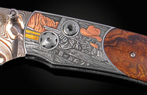 Western-themed knife with Damascus steel blade and engraved handle featuring a cowboy, copper mountains, wood, and black gemstone.