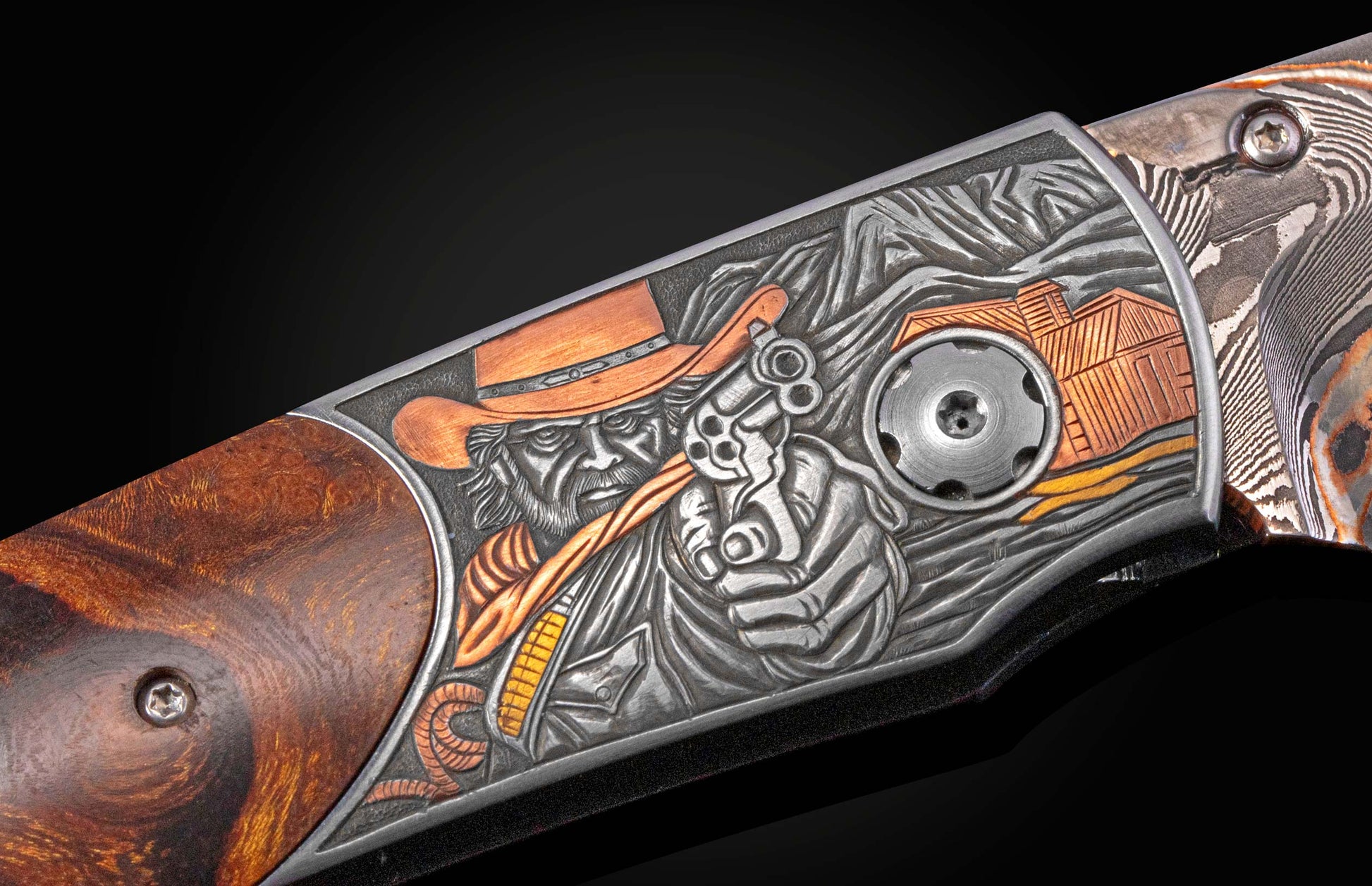 Custom folding knife with an ornate engraved metal handle depicting a cowboy, mountains, and a cabin, complemented by a wood burl grip and Damascus blade.