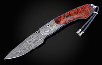 Folding knife with Damascus steel blade , hand engraving, and desert ironwood handle on a black background