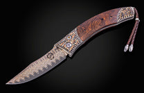 Ornate folding knife with a wavy Damascus blade, rich wood handle, intricate copper sunrise metalwork, and leather lanyard.