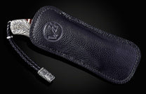 Black leather key case with silver accents on a black background