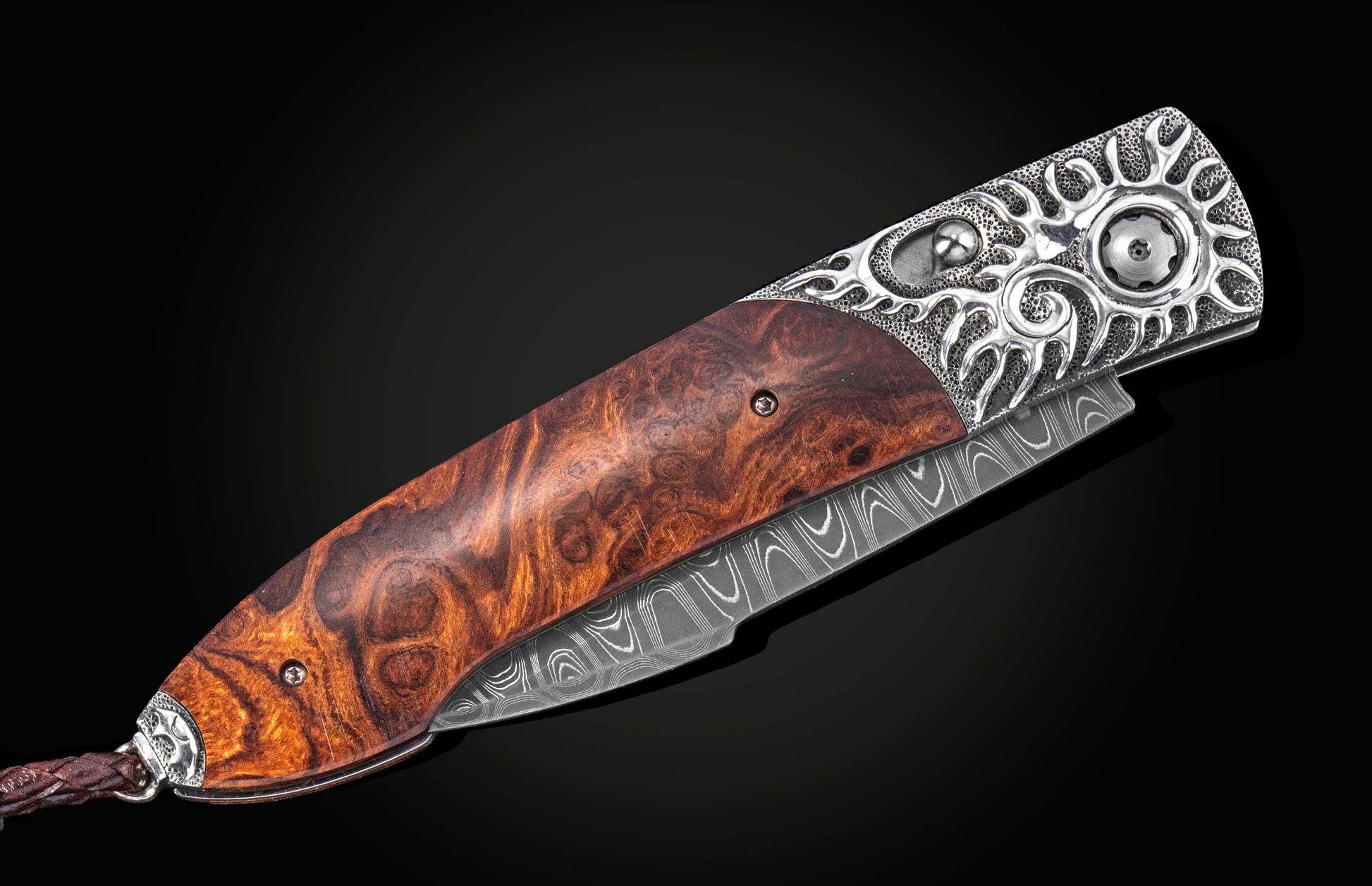 B22 Iron Flare folding knife with damascus steel blade and rich brown burl wood handle, featuring intricate silver filigree bolster and side view on black background
