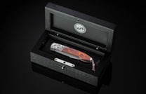 Stainless steel folding knife with wood handle and engraved bolster by B22, displayed in black presentation box with logo.