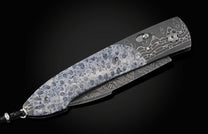 Decorative folding knife with intricate patterns on a dark background