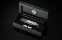 Decorative folding knife with intricate patterns on a dark background