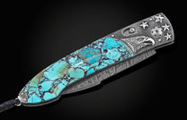 Custom knife with turquoise and black stone handle, silver eagle head, stars, and Damascus steel blade, with a black braided lanyard.