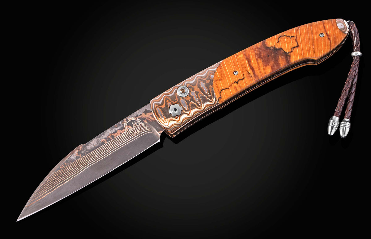 Luxury B22 Sunset folding knife with damascus steel blade and orange wood handle, featuring intricate wave patterns and braided leather lanyard, side view on black background
