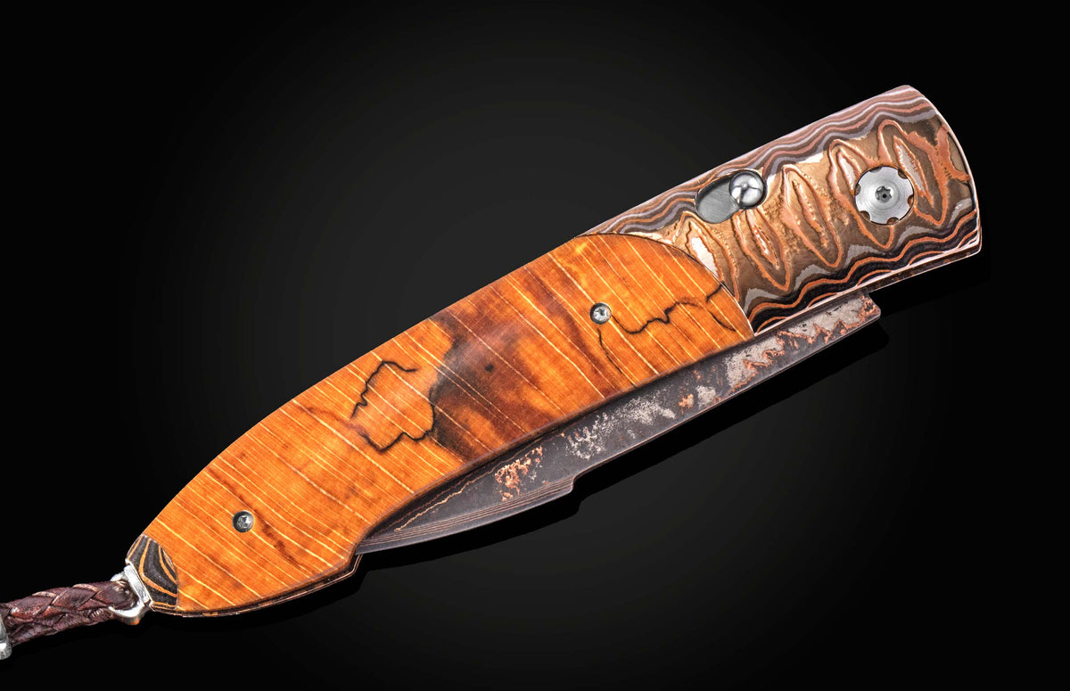 Luxury B22 Sunset folding knife with amber wood handle, marbled copper bolster, and partially open blade, side view on black background