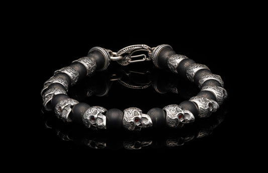 Garnet Shaman skull bracelet with black beads and silver accents, displayed on a reflective surface.