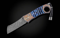 Luxury cigar cutter with damascus steel blade and blue resin handle, featuring ornate gold inlays and braided cord, side view on black background