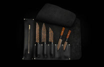 K22-BLK-W|Five chef knives with black flare patterned blades, displayed in an open black leather roll-up case with gold accents.