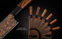 Black Flare steak knife set with orange patterned blades and wooden handles, displayed in a dark hardwood block.