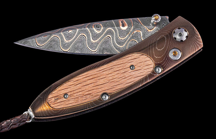 Folding knife with wooden handle and decorative blade on a black background
