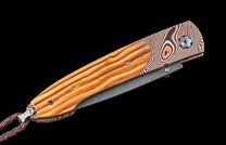 Folding knife with wooden handle and Damascus steel blade on a black background