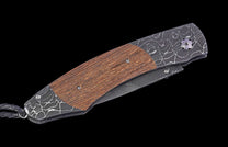 Foldable knife with wooden handle and engraved blade on a black background