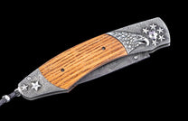 Decorative folding knife with wooden handle and damascus blade on a black background