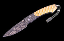 Folding knife with wooden handle and engraved blade on a black background