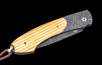 Folding knife with wooden handle and engraved blade on a black background