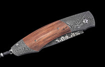 William Henry knife with wooden handle and damascus steel blade on a black background
