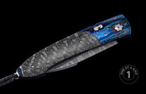 Automatic folding knife with dark grey carbon fiber scales, blue titanium frame with gold cracked pattern, Damascus blade, and braided leather lanyard.