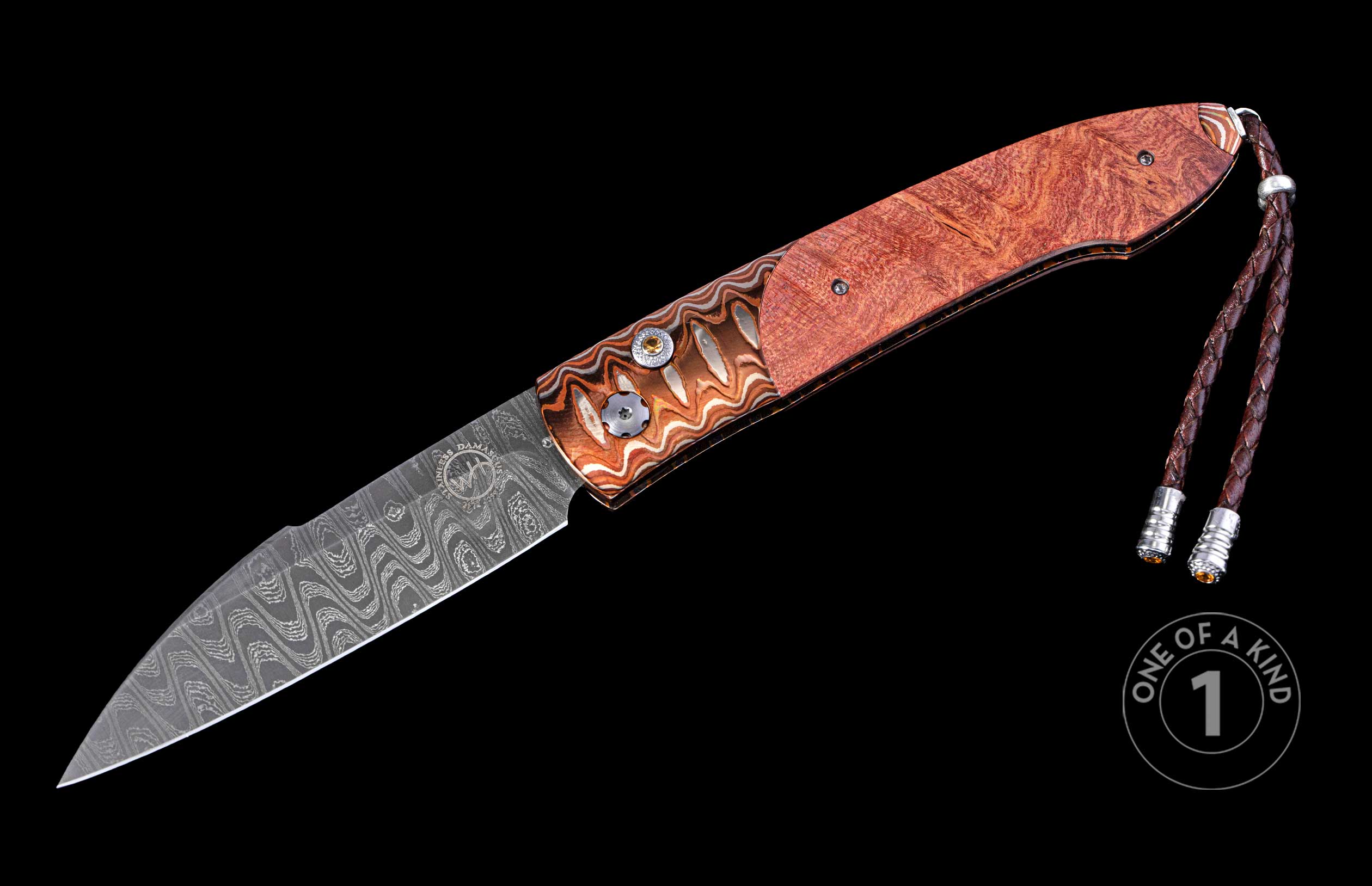 Elegant folding knife featuring a wavy Damascus steel blade, reddish-brown wood and copper-toned handle with gem accents, and a braided leather lanyard.