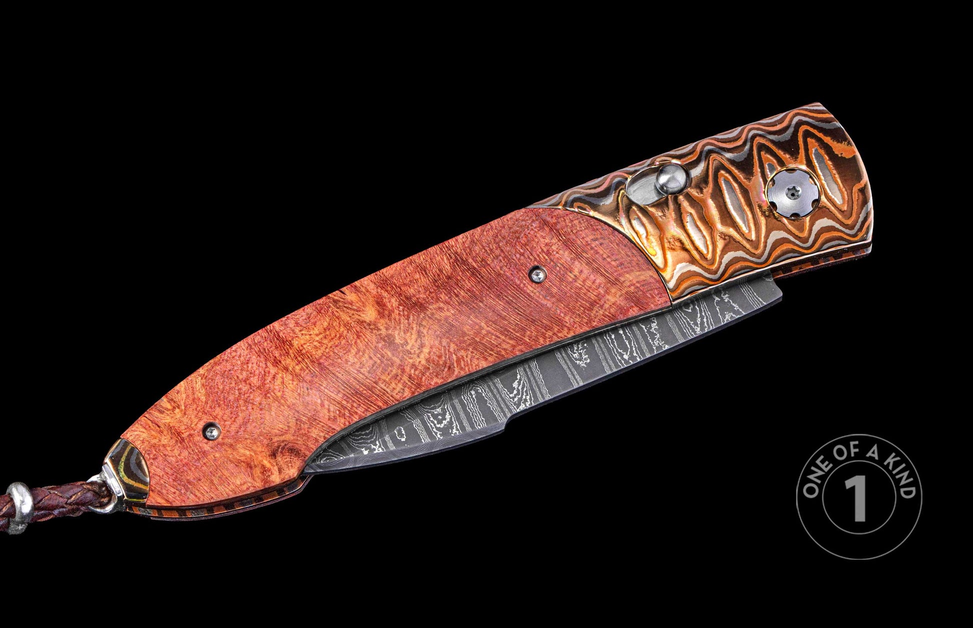 Closed folding knife with reddish-brown burl wood handle, copper and silver patterned bolsters, Damascus steel blade, and braided leather lanyard.