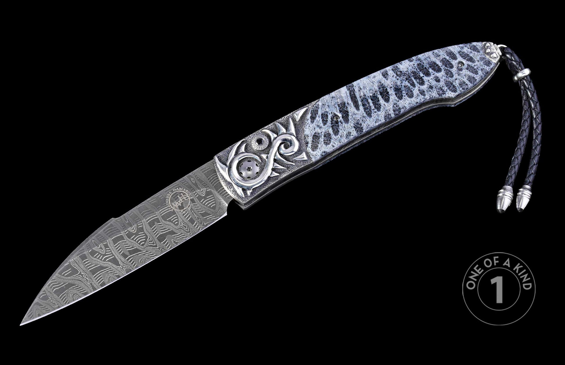 Decorative folding knife with a patterned Damascus blade, a white and black spotted handle with ornate silver carvings, and a black braided leather lanyard.