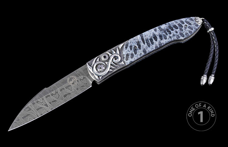 Decorative folding knife with a patterned Damascus blade, a white and black spotted handle with ornate silver carvings, and a black braided leather lanyard.