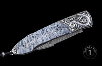 Custom folding knife with a unique light grey handle, ornate silver bolsters, a Damascus blade, and a black lanyard.