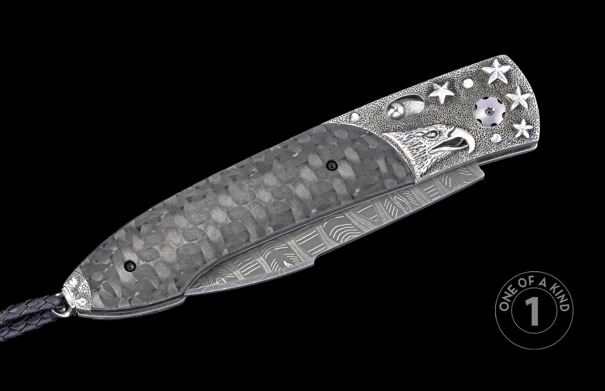 Folding knife with grey carbon fiber handle, engraved silver eagle head, stars, Damascus steel blade, and black braided lanyard.